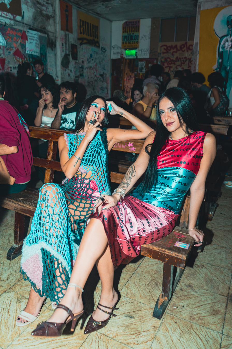 Dos modelos sentadas riendo con prendas de la colección